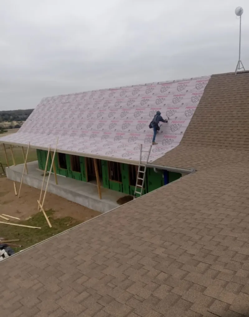 Worker preparing underlayment for a metal roof installation in Hales Corners